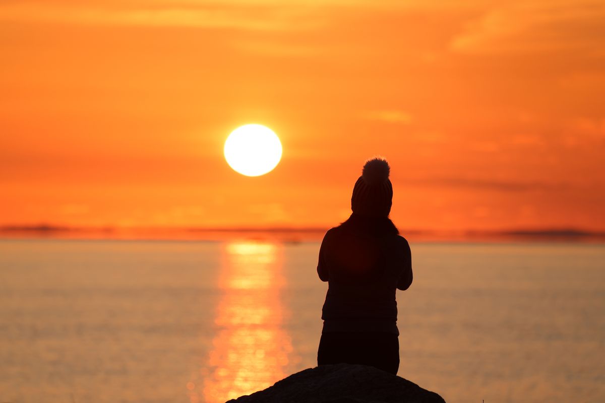 Silhouette of a Person Sitting at a Seashore and Enjoying a Sunset ...