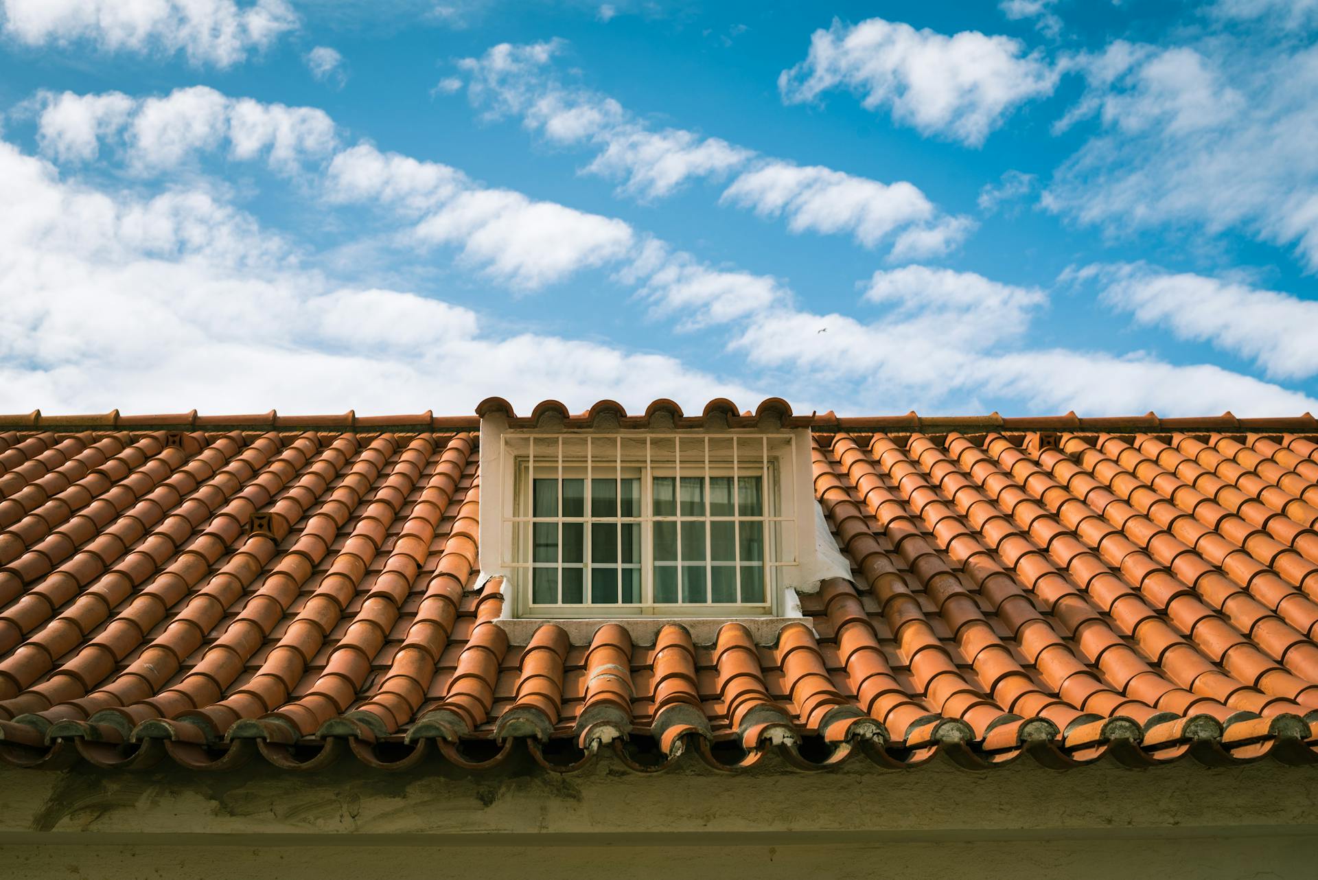 Close-up of a terracotta tiled roof with a skylight window in sunny Marbella, Spain.