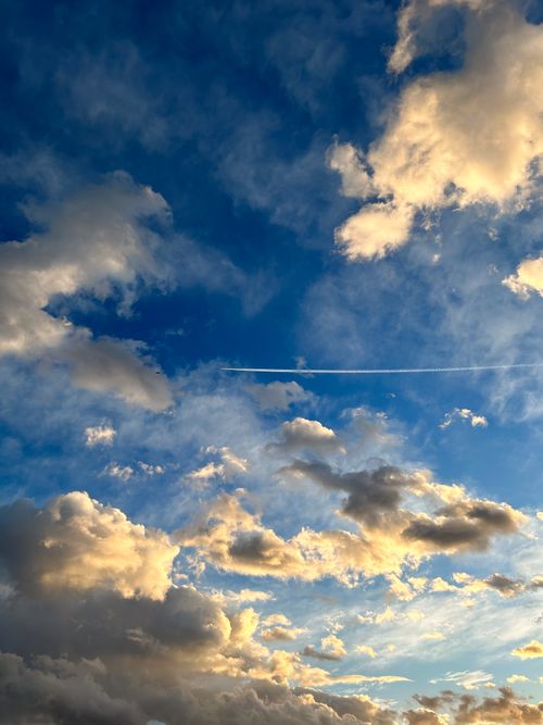 Free Vibrant summer sky with dramatic clouds and a distinct airplane trail. Stock Photo