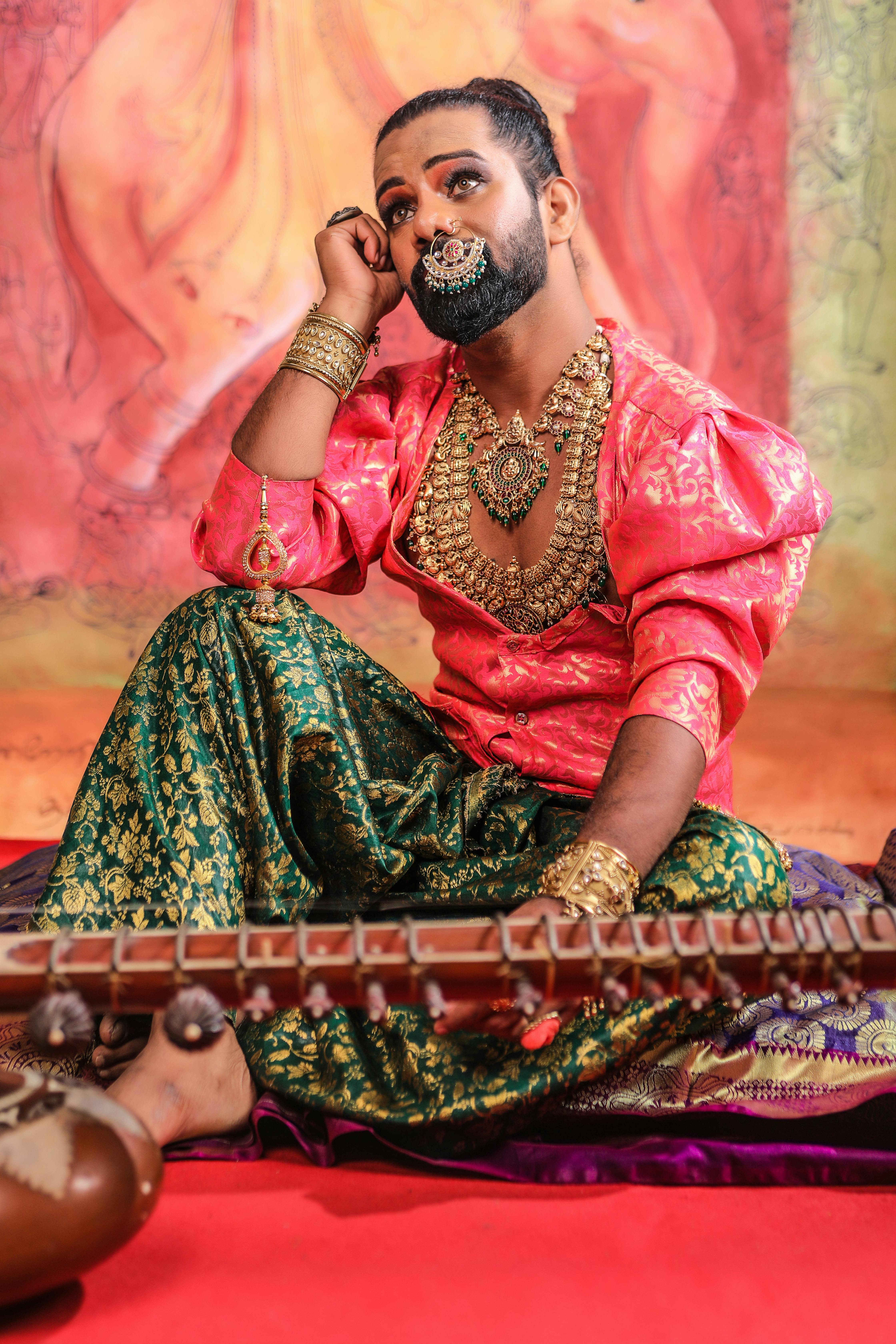 A man in traditional Indian attire sits with a musical instrument, exuding cultural elegance.