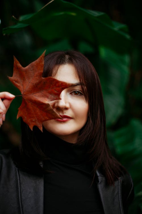 Brunette Woman Holding Fallen Leaf in Hand