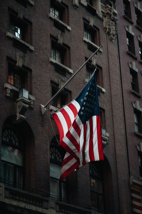 Free United States flag hanging on a historic building in New York City, NY. Stock Photo