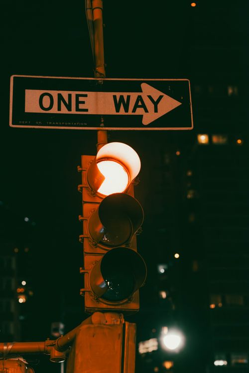 Free A one way sign and traffic light illuminated at night in New York City. Stock Photo