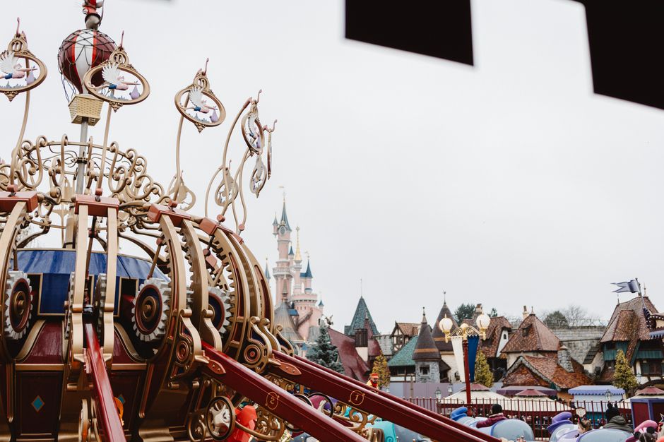 A whimsical view of an ornate ride with fairytale architecture at Disneyland Paris.