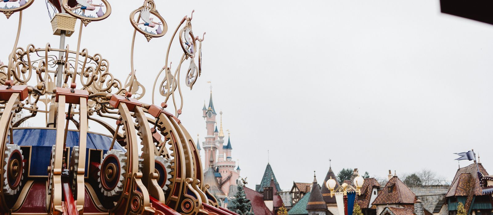 A whimsical view of an ornate ride with fairytale architecture at Disneyland Paris.