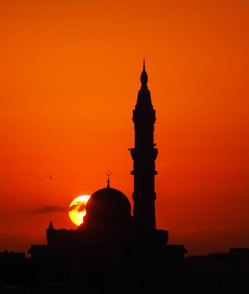 Free Stunning silhouette of a mosque and minaret against an orange sunset in Dubai. Stock Photo