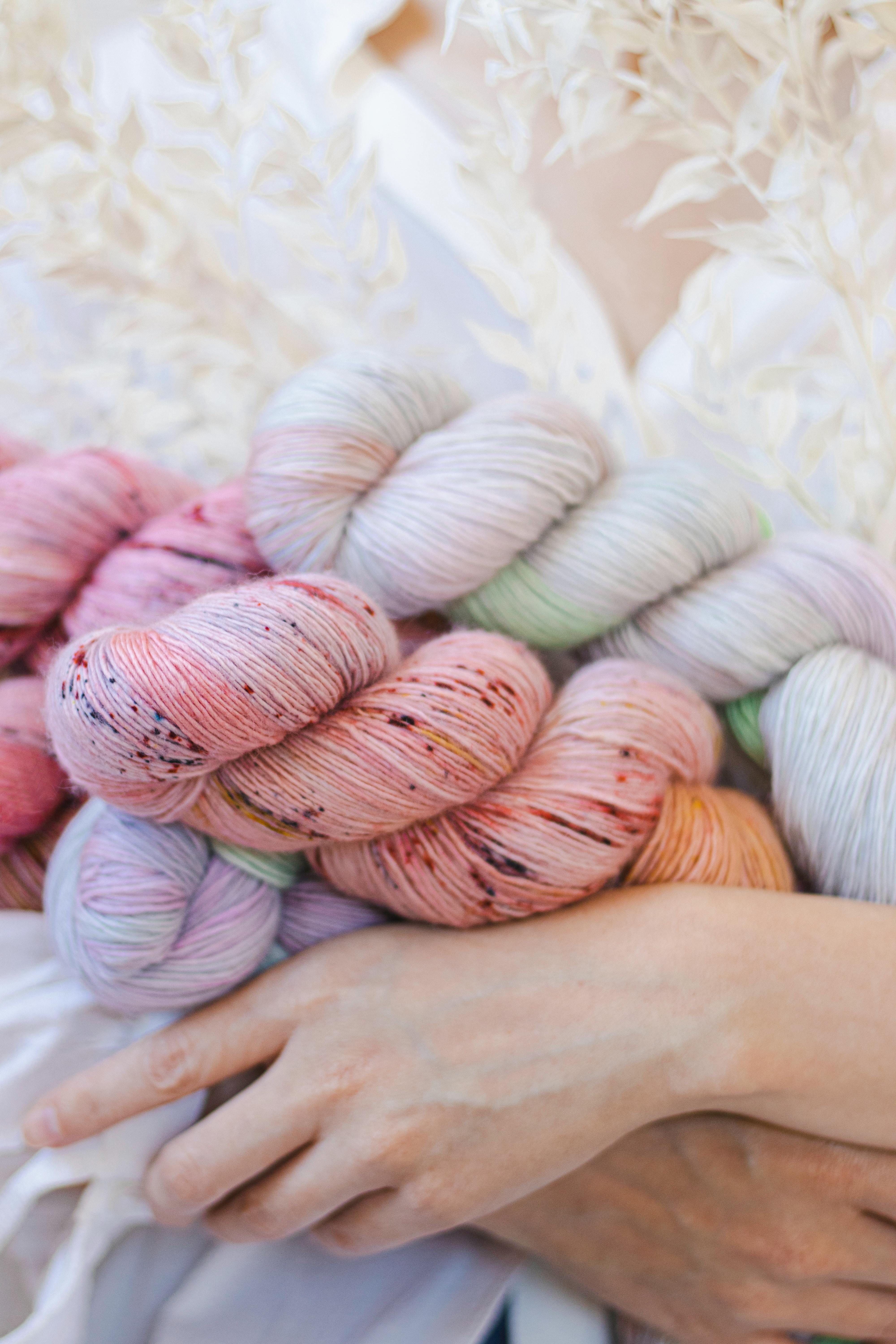 Close-up of a person holding vibrant yarn skeins, perfect for crafting projects.