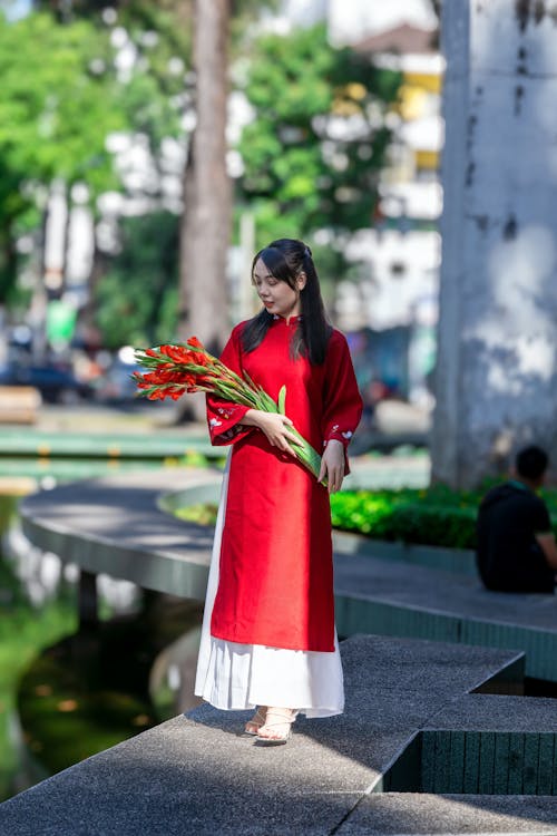 Beautiful Brunette Woman with Red Flowers in Hands