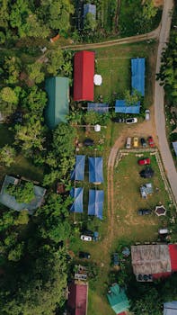 Top-down view of an agricultural area with colorful roofs and lush trees.