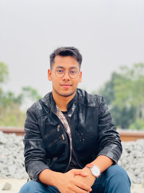 Free Portrait of a young man in glasses and leather jacket sitting outdoors. Stock Photo