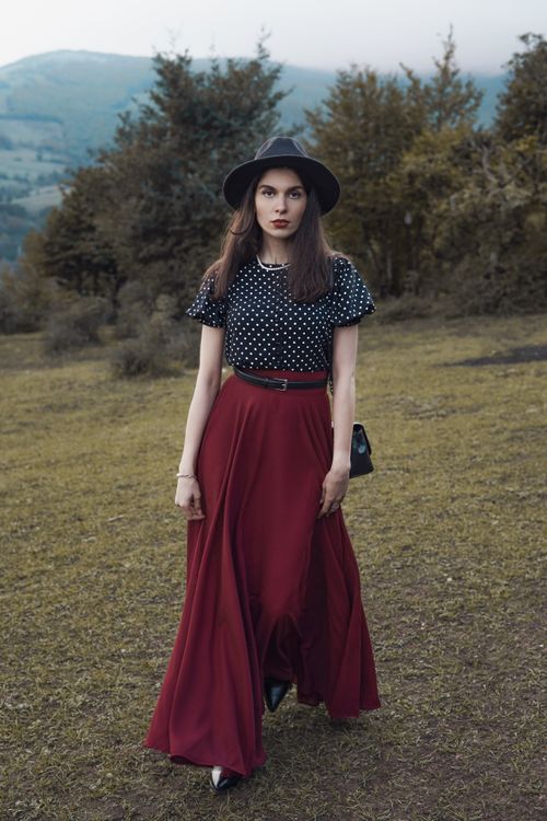 Free Fashion portrait of a woman in a polka-dot blouse and burgundy skirt, posing outdoors with a retro hat. Stock Photo