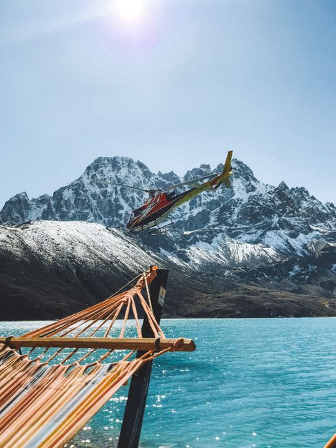 Helicopter flying over a tranquil lake framed by Himalayan peaks in Nepal