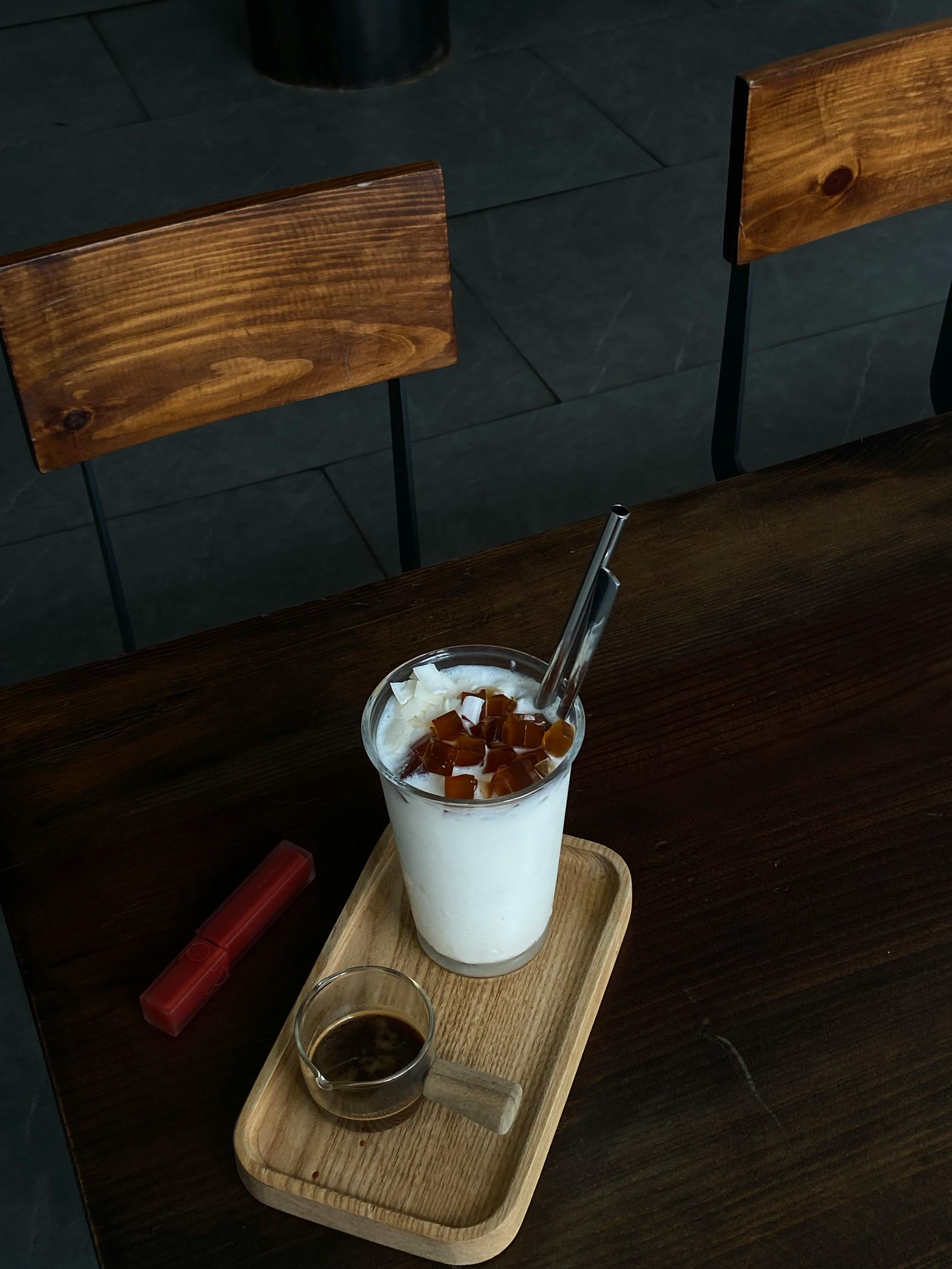 A wooden tray with a milk drink and coffee on a cafe table.