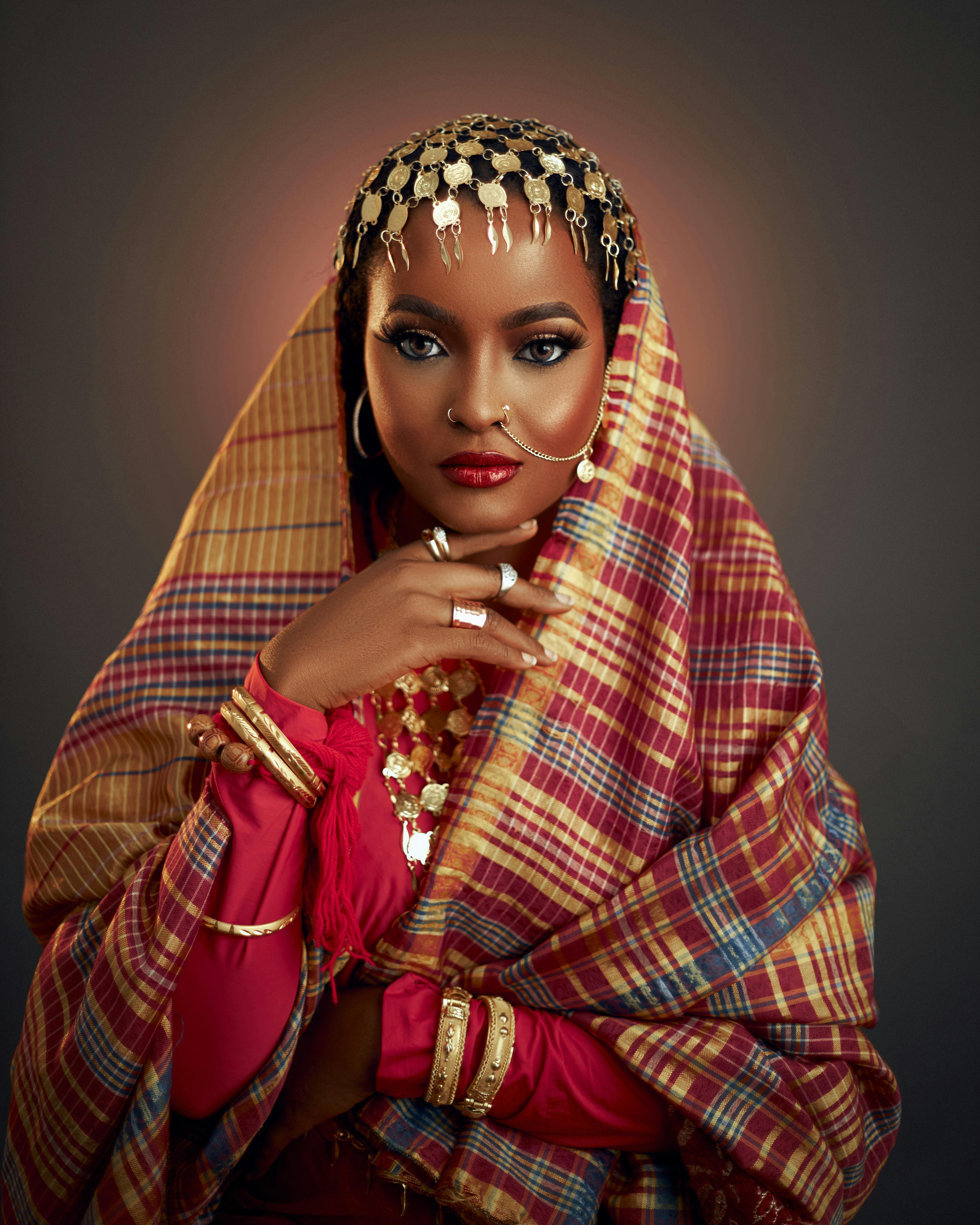Portrait of a woman in colorful traditional attire with ornate jewelry and headscarf.