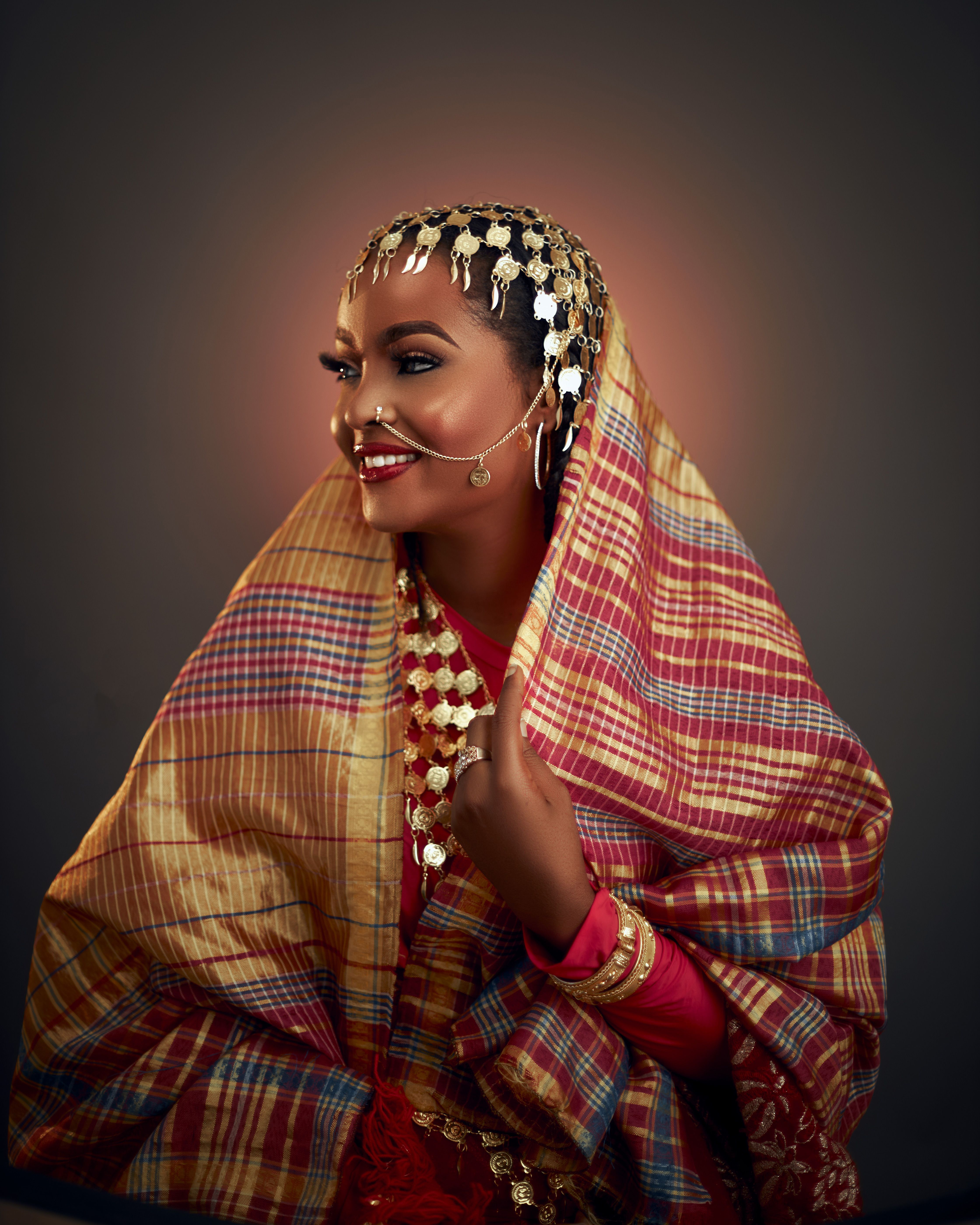 Portrait of an African woman wearing colorful traditional attire and jewelry, smiling gracefully.