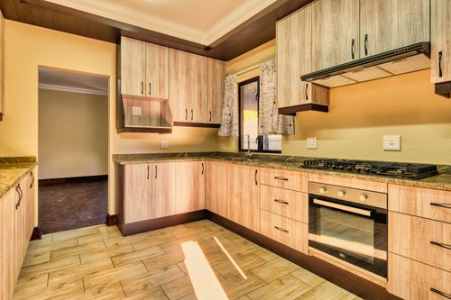 Free Sleek modern kitchen featuring wooden cabinets and a built-in oven with natural lighting. Stock Photo