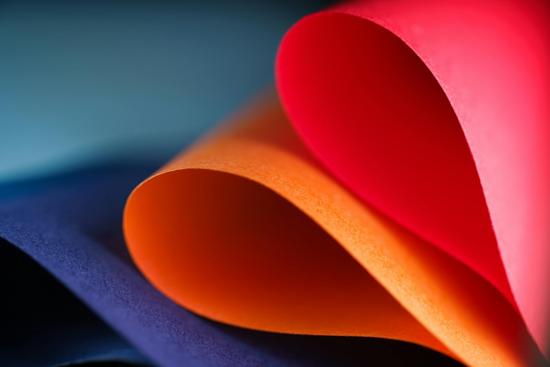 Vibrant abstract design of colorful curved paper sheets in blue, orange, and red hues.