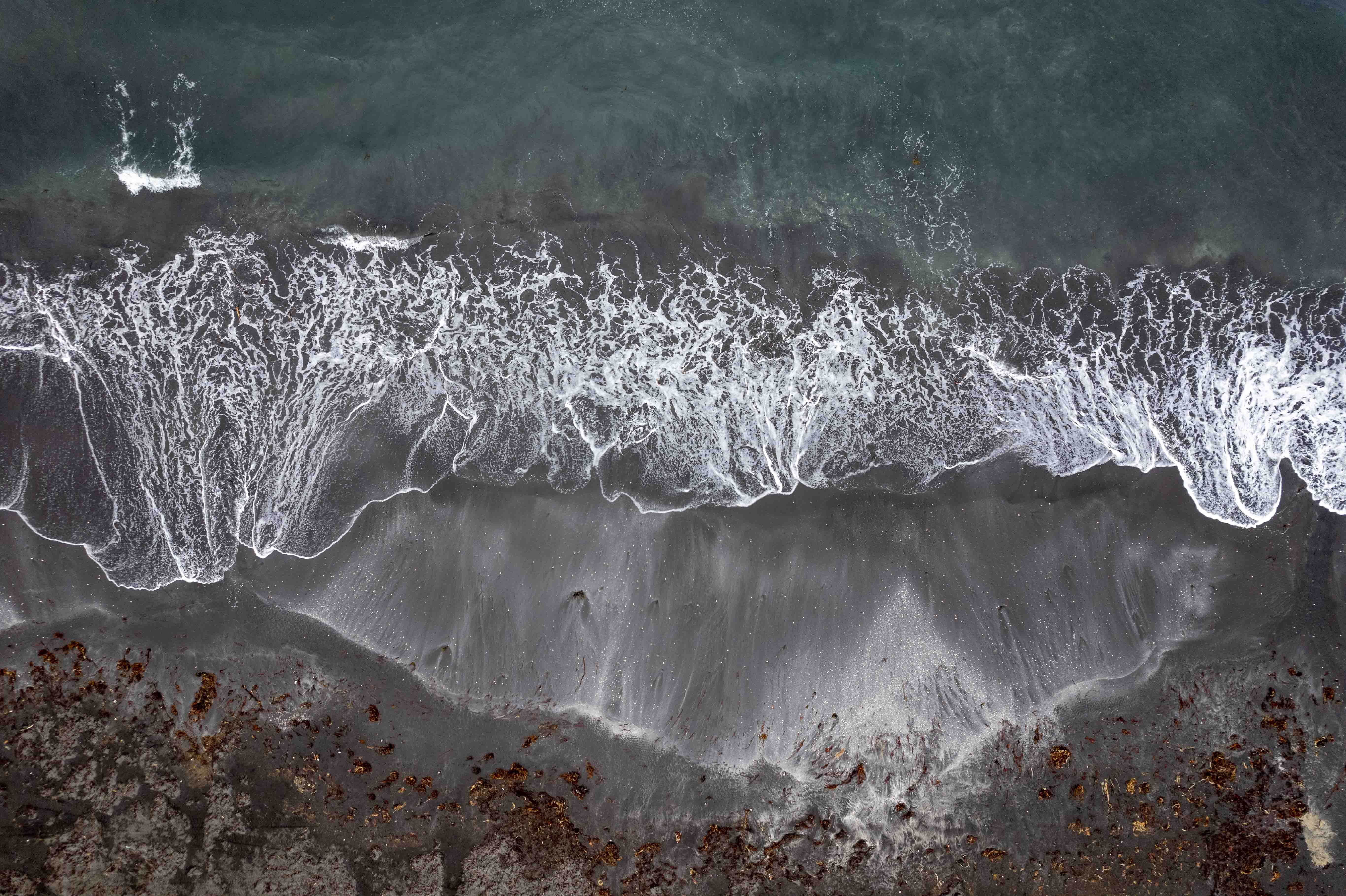 Outstanding Helicopter Tour over the Reykjanes Volcano Area from Reykjavik Review Review 2026 - Dramatic aerial shot showcasing the waves crashing on a black sand beach in Húsavík, Iceland.