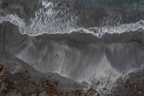 Free Aerial view capturing the stunning black sand beach waves of Húsavík, Iceland. Stock Photo