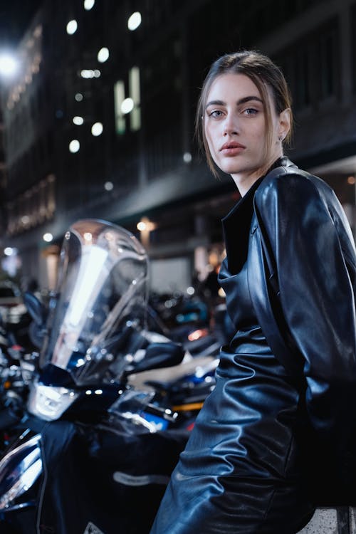 Young Woman in Leather Dress and Jacket Next to Parked Motorcycles