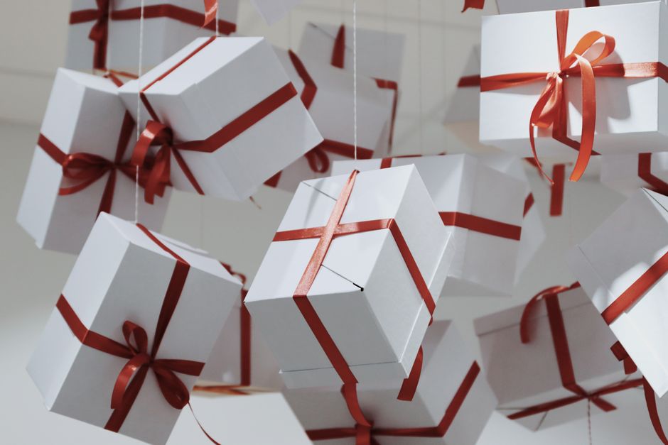 Elegant white gift boxes tied with red ribbons suspended artfully.