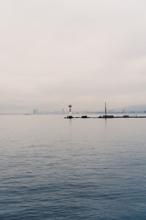 Free Lighthouse on a foggy seashore in Izmir, capturing the serene dawn over the sea. Stock Photo