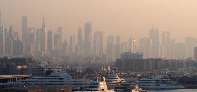 Dubai Marina with luxury yachts against a skyline of iconic skyscrapers in the morning light.