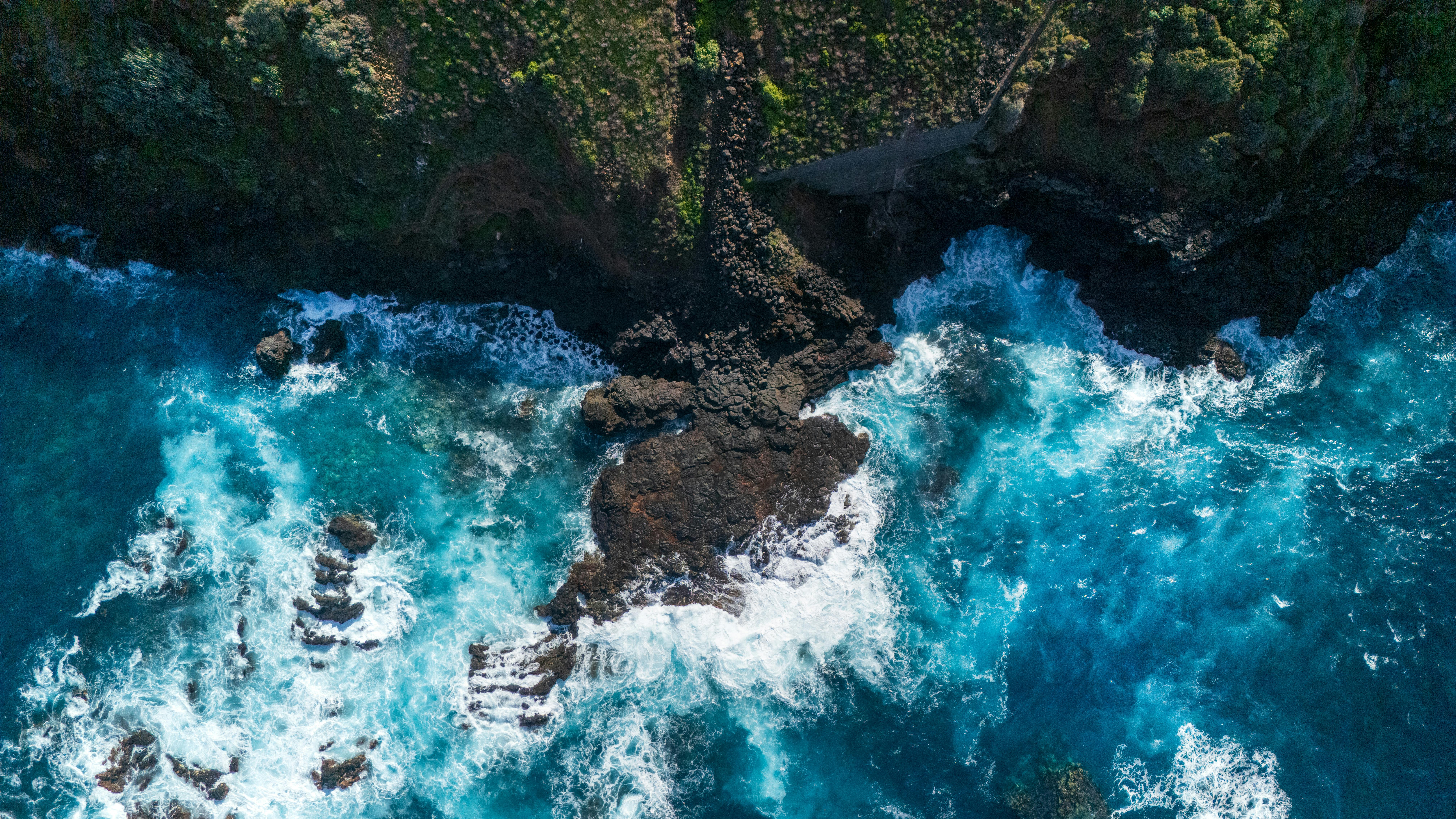 A stunning aerial shot of the rugged cliffs and blue waves at Ла Калета, Spain.