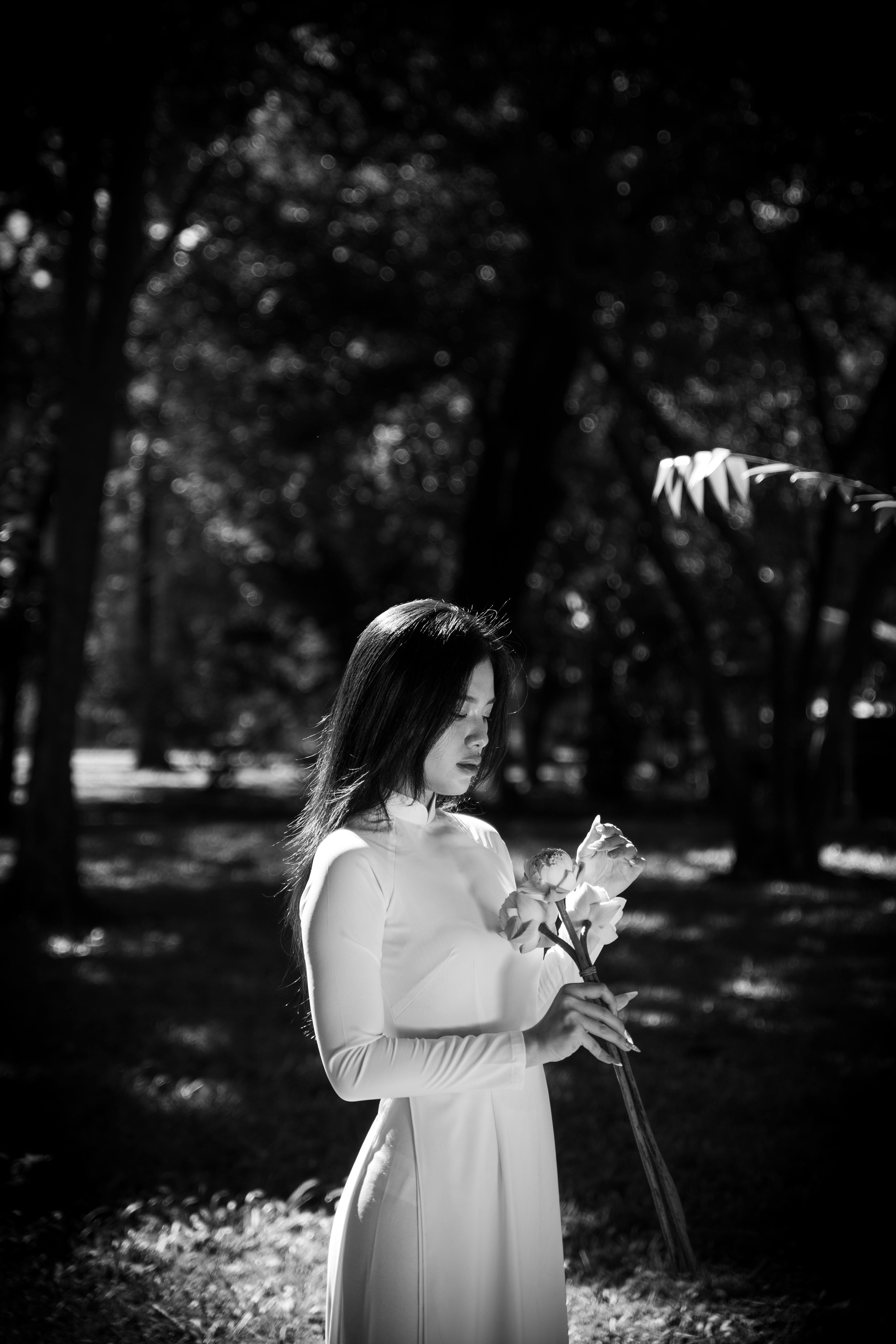 A serene black and white portrait of a woman with flowers in a park, Ho Chi Minh City.
