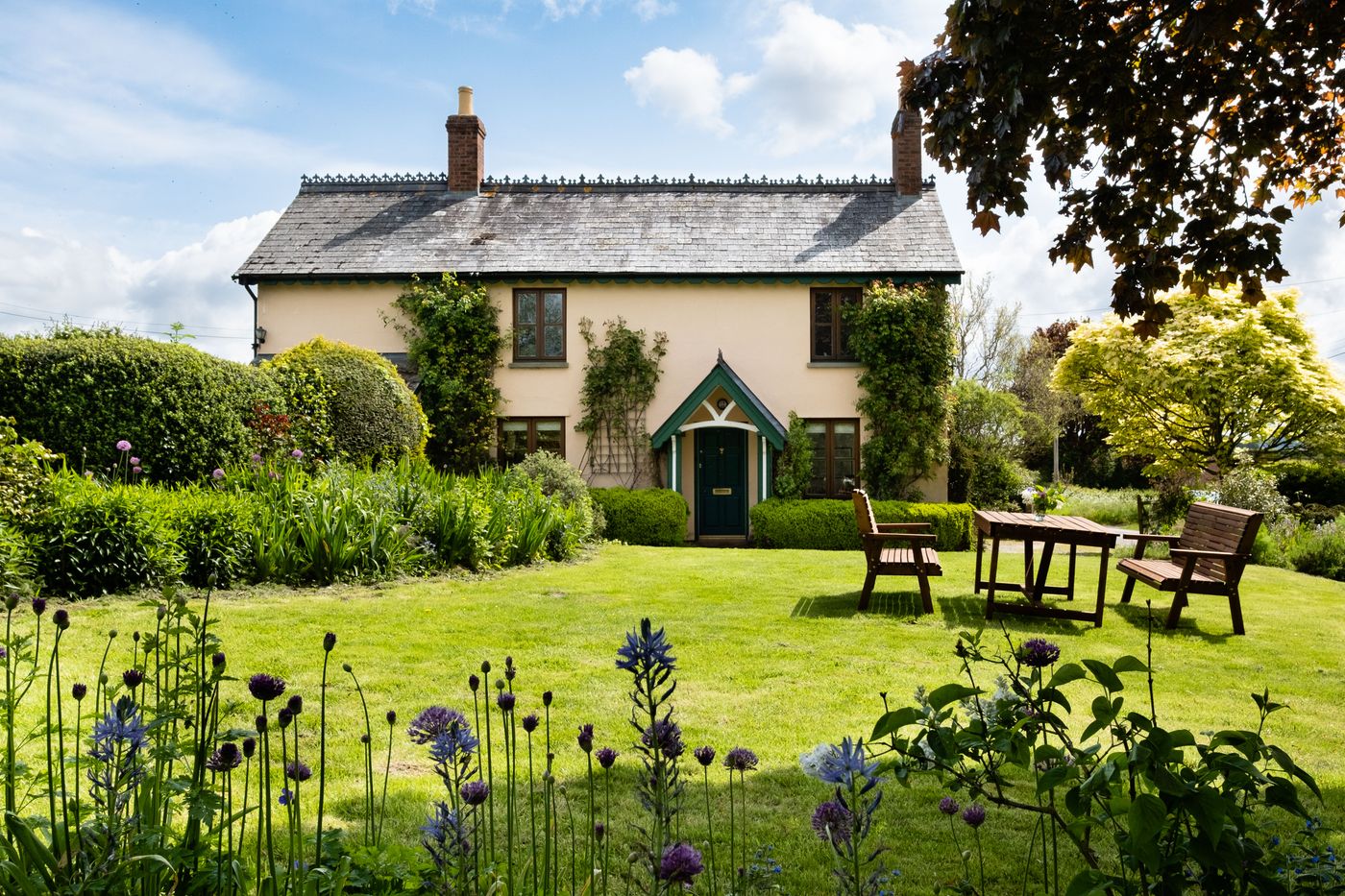 Idyllic English cottage garden with lawn, flower borders and seating area