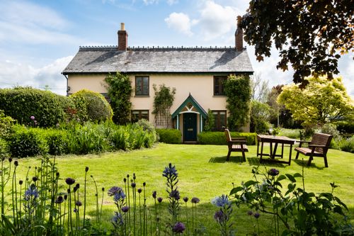 Free Idyllic cottage garden scene in Hereford with lush greenery and seating area. Stock Photo