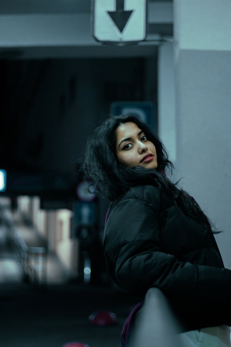 Brunette Woman In Black Puffer Jacket Posing In A Street