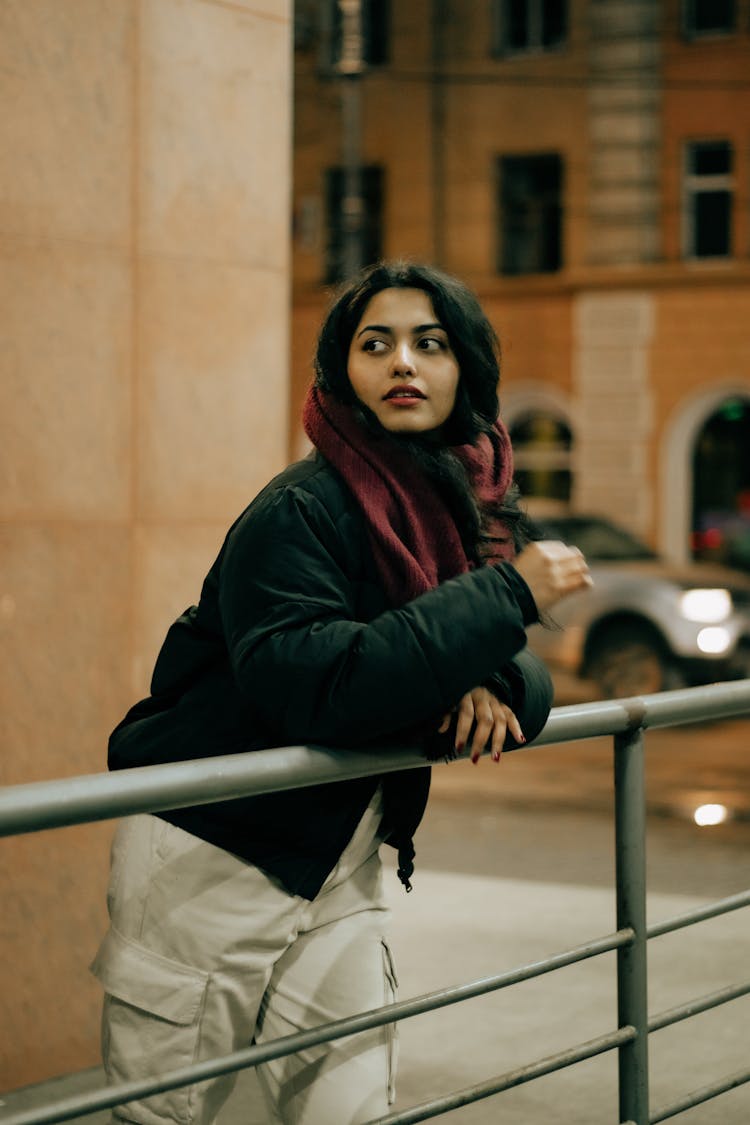 Brunette Woman In Black Puffer Jacket Leaning On Metal Railing