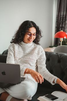 Smiling woman using laptop and taking notes, enjoying a productive day indoors.
