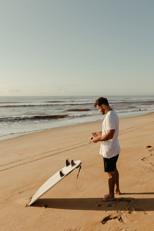 Man Standing on the Beach with a Surfboard 