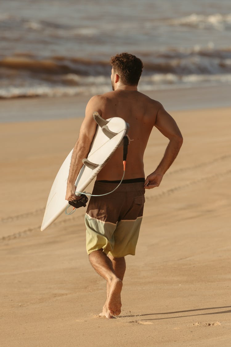 Shirtless Man With Surfboard Running Towards Water