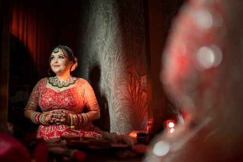 Free A smiling bride wearing a dazzling red lehenga and traditional jewelry, evoking luxury and grace. Stock Photo
