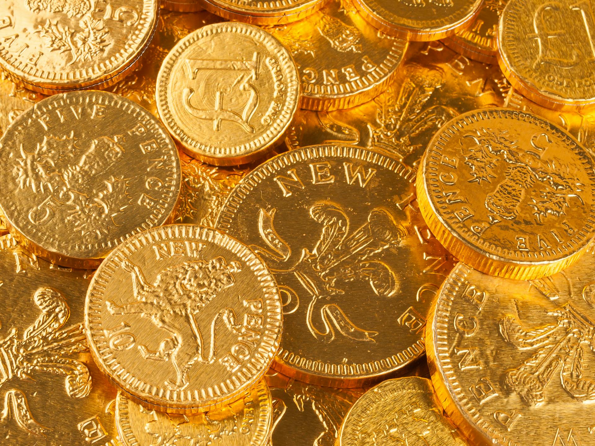 A close-up of gold-colored British pound and pence coins, showcasing intricate details.