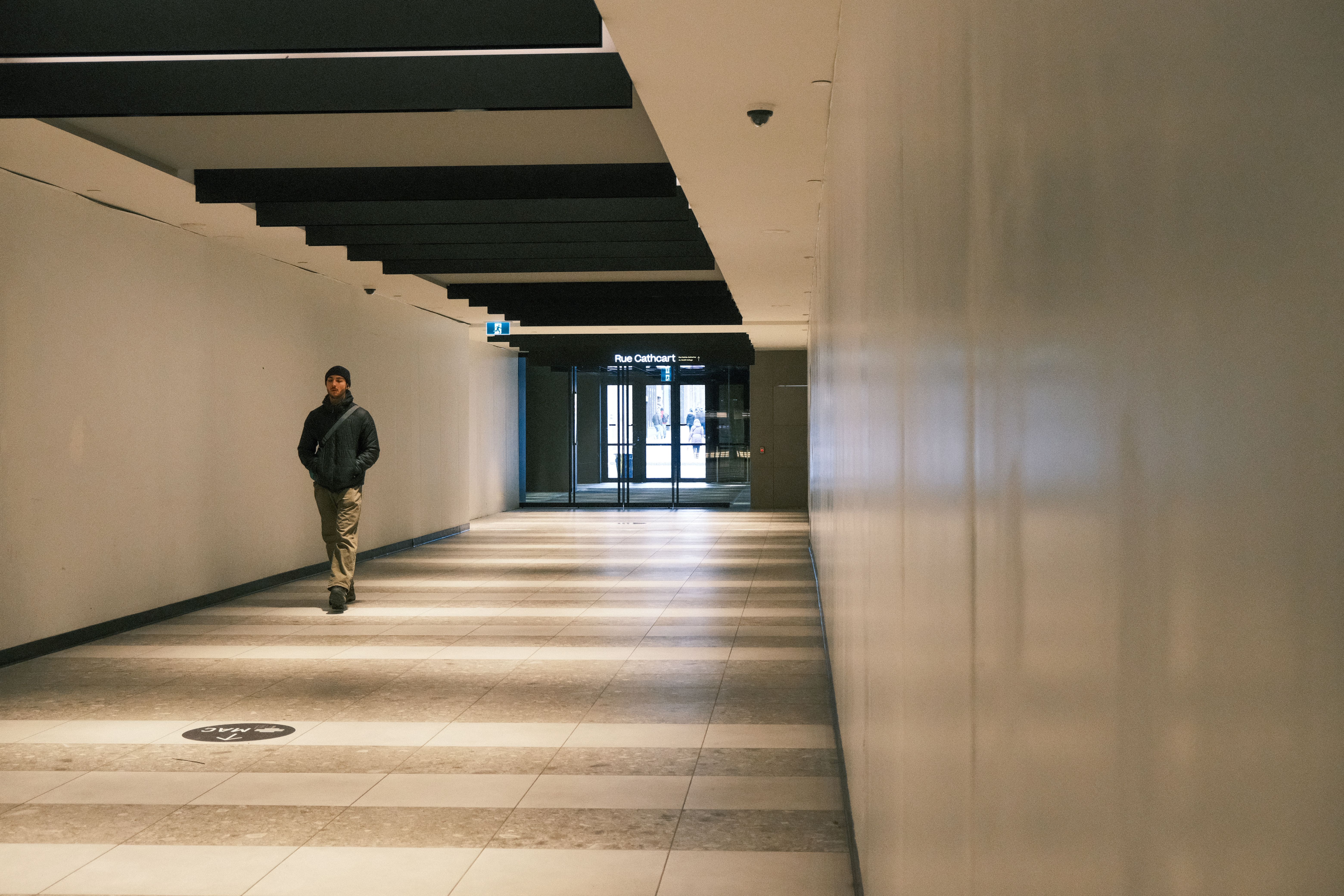 A man walking in a modern indoor corridor with architectural details.