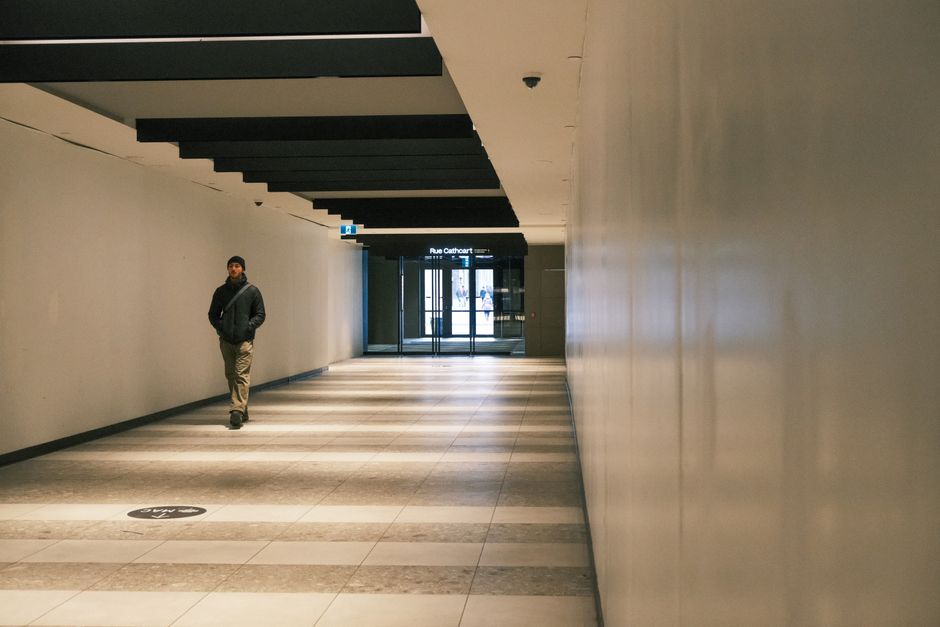 A man walking in a modern indoor corridor with architectural details.