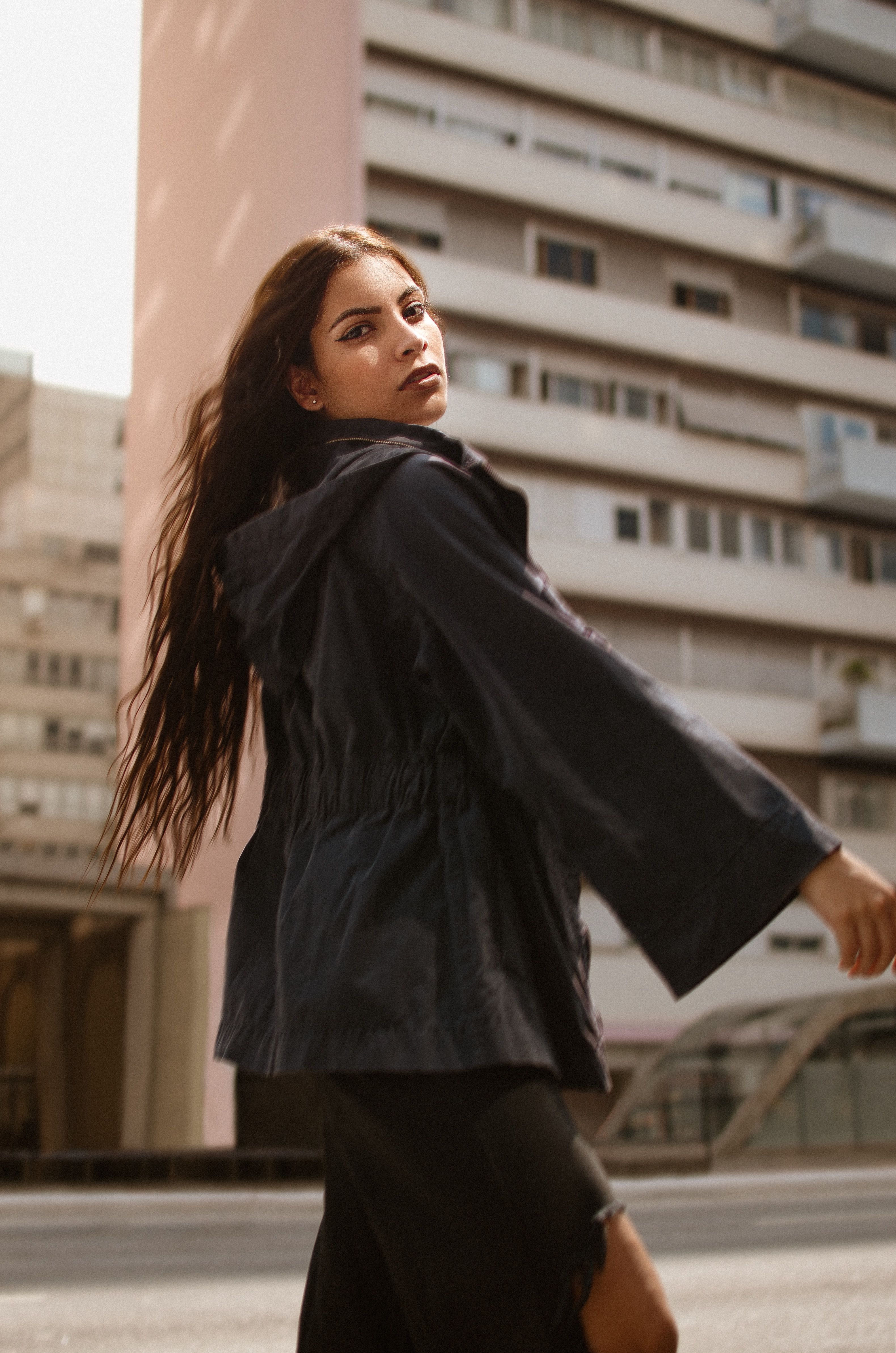 A stylish woman in a coat poses on a city street, capturing urban fashion essence.