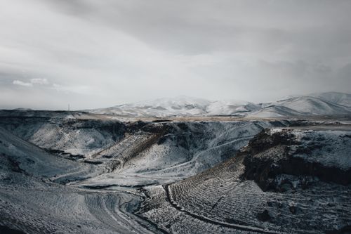 Free Majestic winter landscape featuring a snowy mountain range and valley under a cloudy sky. Stock Photo