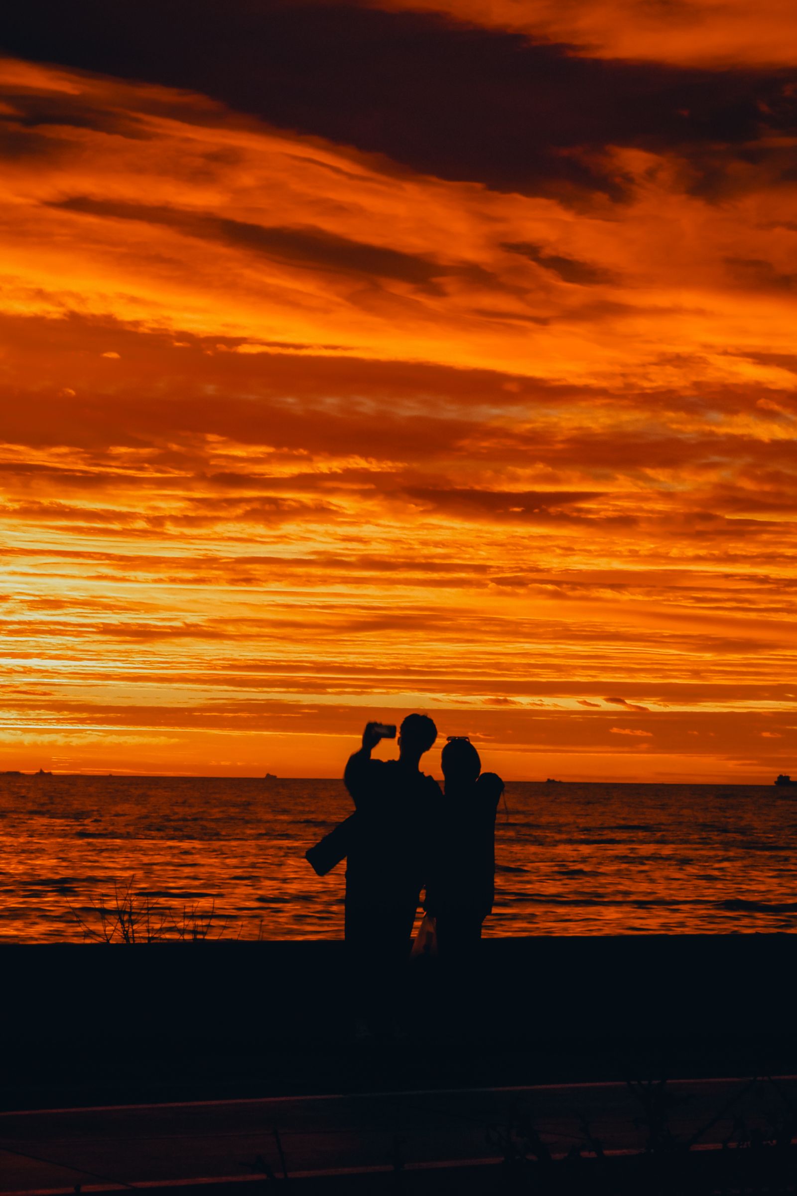 Silhouette of Couple Near Body of Water During Sunset · Free Stock Photo