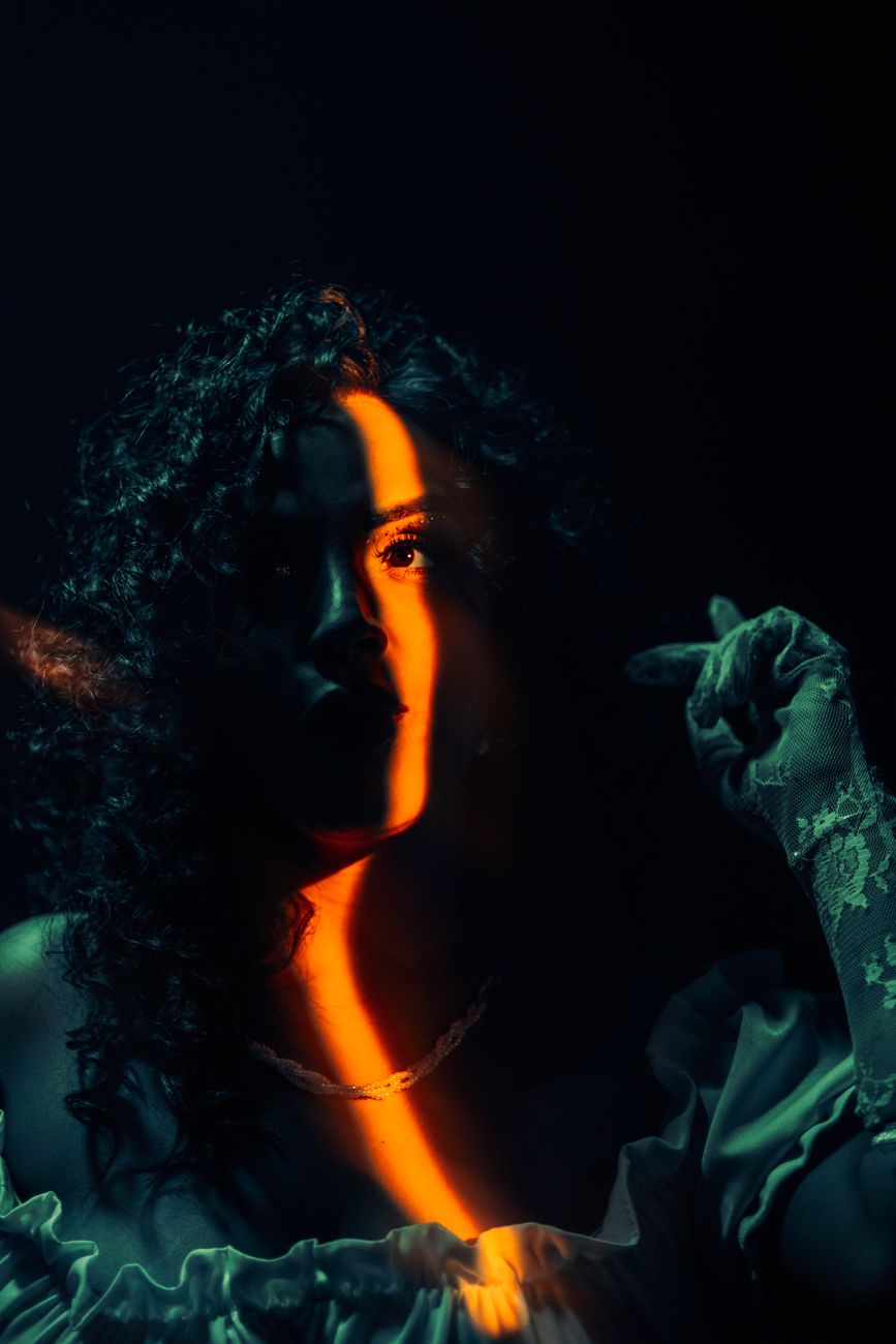 A mysterious portrait of a woman in a dark setting, illuminated by dramatic light.