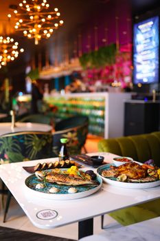 Vibrant restaurant setting featuring gourmet fish and chicken dishes on stylish plates.