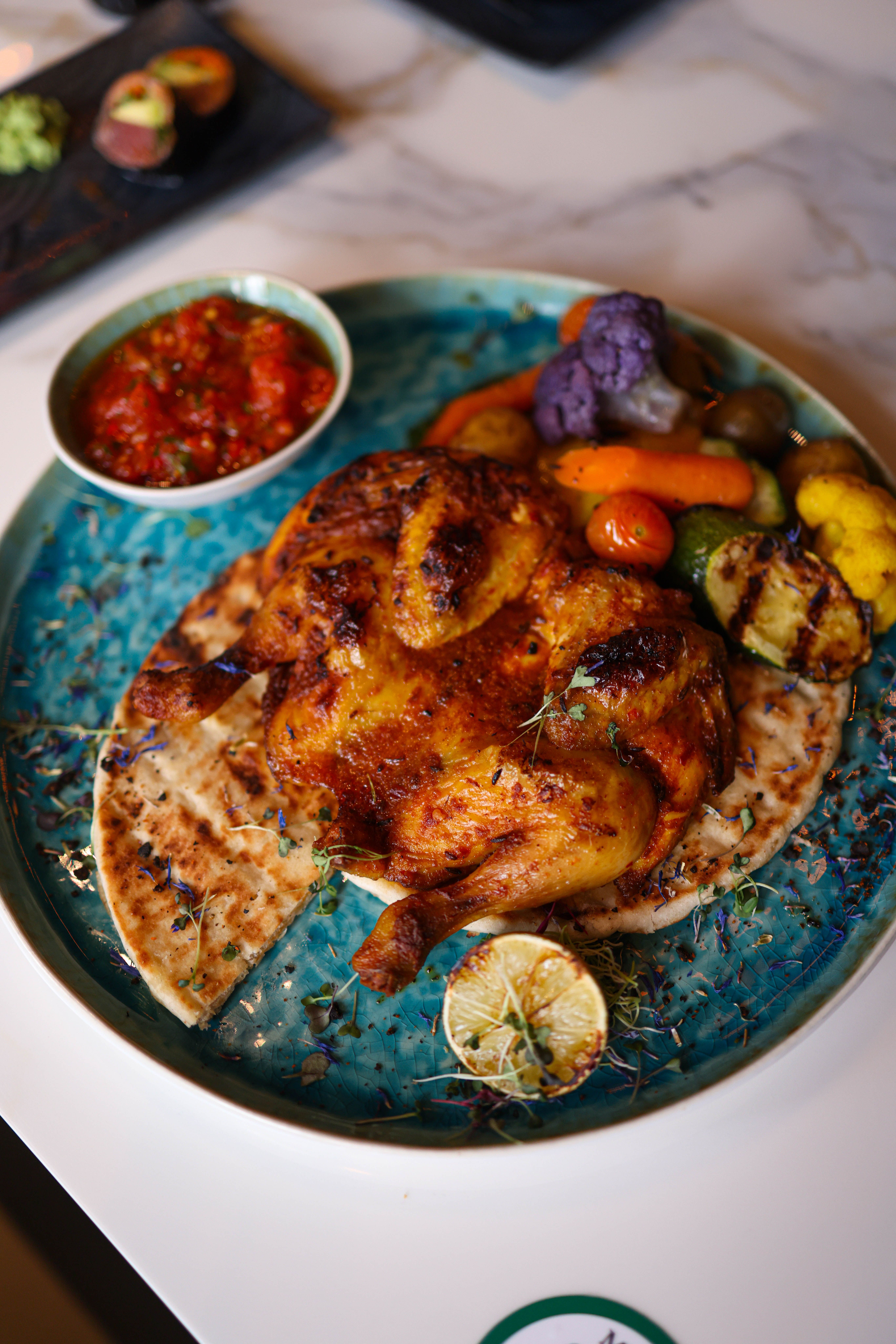 Delicious grilled chicken paired with colorful vegetables on flatbread, served with salsa.