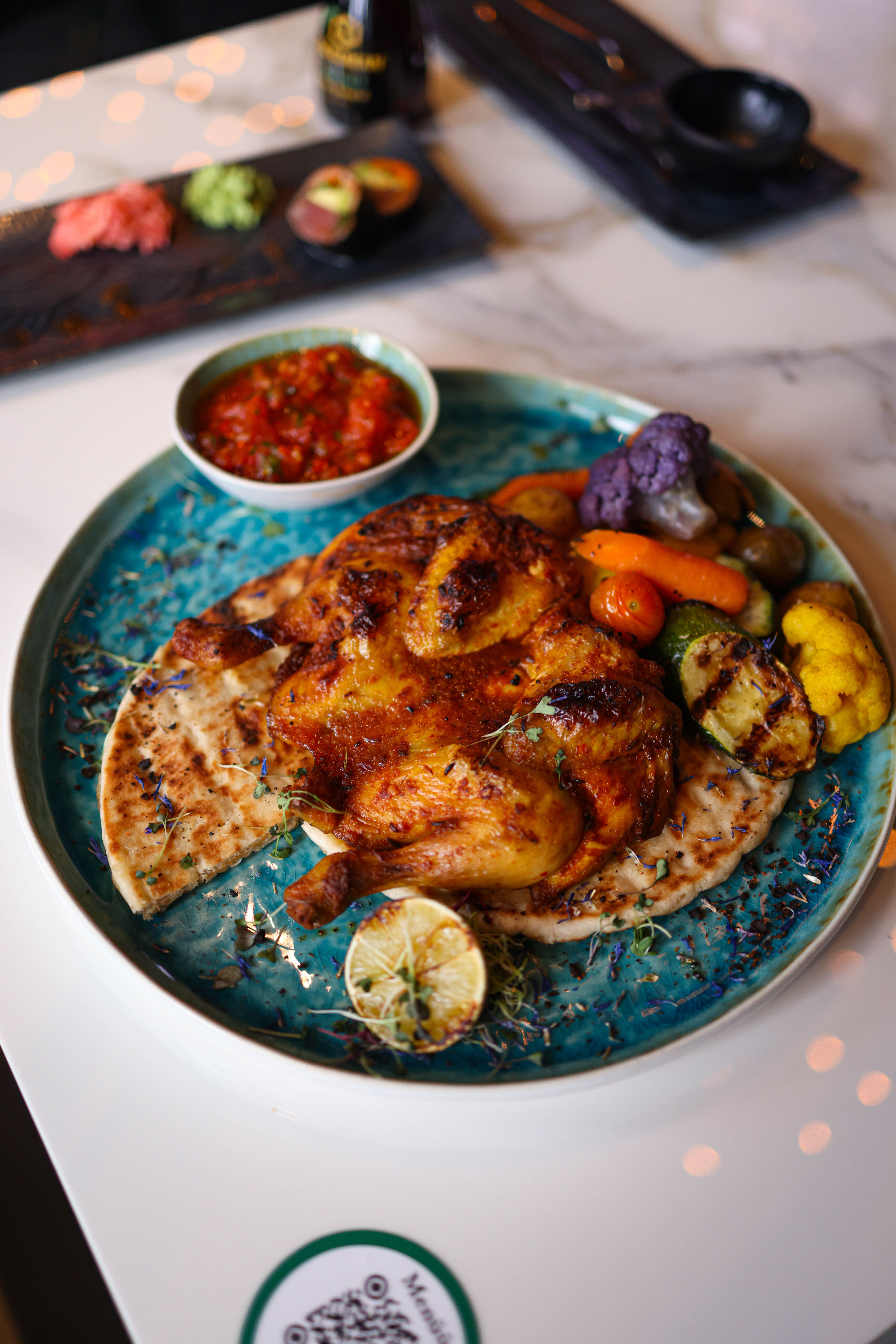 Delicious grilled chicken with vegetables and sauce on a blue plate, perfect for a hearty meal.