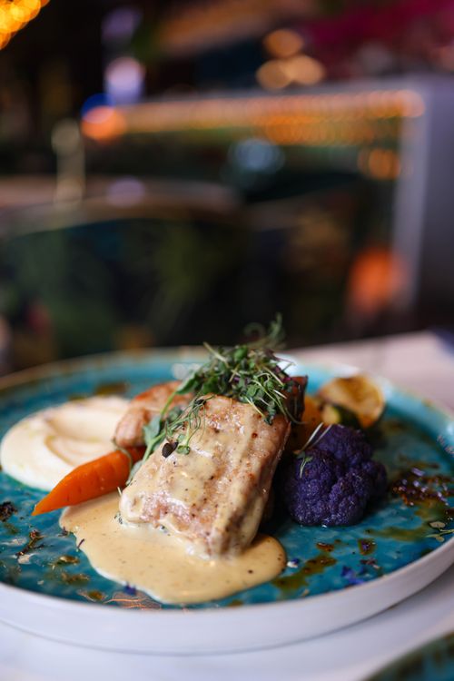 Free Delicious gourmet meal featuring succulent meat with creamy sauce, served with carrots and purple cauliflower garnish. Stock Photo