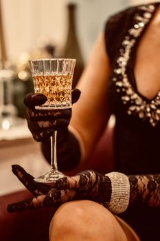A woman in lace gloves elegantly holding a crystal wine glass, exuding luxury and sophistication.