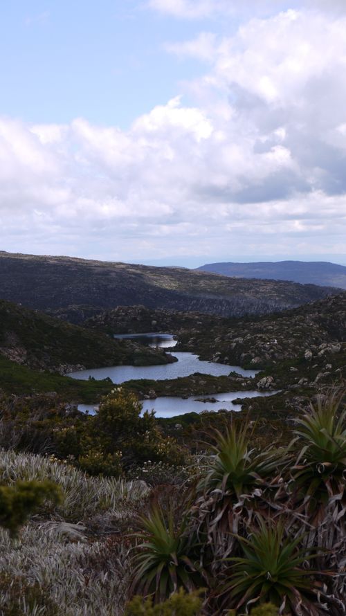 Free A breathtaking view of a mountain valley with lakes and lush greenery under a cloudy sky. Stock Photo